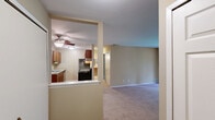 Located at 7160 Round Hill Dr in Waterford, MI, this one-bedroom, two-bathroom unit offers a well-organized single-floor layout designed for comfortable everyday living. The combined kitchen and living room area forms the heart of the home, with the kitchen featuring warm wood-toned cabinetry, light countertops, a double sink, and a full suite of appliances including an electric range and refrigerator. The flooring transitions from hardwood-style in the kitchen to soft carpeting throughout the living areas. The spacious living room is bathed in natural light, with a sliding glass door opening onto a private balcony that overlooks lush greenery, creating a pleasant indoor-outdoor connection. The bedroom is generously sized, finished with neutral-toned carpet, and includes access to both a dedicated closet and an en-suite bathroom. Two bathrooms serve the unit, each featuring tile flooring and clean, functional fixtures, including a tub-shower combination. Throughout the unit, warm beige walls and white trim create a cohesive, neutral aesthetic. A wood-floored entryway provides a welcoming transition into the home, and ample wall outlets are present throughout for added convenience.