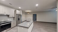 Located at 17448 N Eldridge Parkway in Tomball, Texas, this well-appointed 2-bedroom, 1-bathroom residence offers a thoughtfully designed single-floor layout that maximizes functionality and comfort. The open-concept kitchen and living area serves as the heart of the home, anchored by a striking granite-topped kitchen island with an undermount sink. Light wood-tone cabinetry, a tile backsplash, stainless steel appliances — including a French door refrigerator with ice maker and a slide-in range — and recessed lighting complete the modern kitchen. Wood-look plank flooring flows throughout the main living areas, creating a clean, contemporary aesthetic. The spacious primary bedroom features plush carpeting, a ceiling fan, and a private door leading to an outdoor area, while the second bedroom also offers carpet flooring, a ceiling fan, and a bright window with blinds. The full bathroom includes a soaking tub with a tiled surround and a curved shower rod, finished with granite counters and wood-look flooring. A dedicated laundry room houses side-by-side washer and dryer units alongside wire shelving for additional storage. Two closets provide ample organization throughout the home.
