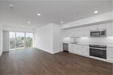 Located in the Echo Park neighborhood of Los Angeles, this modern 2-bedroom, 2-bathroom residence offers a clean, contemporary design throughout. The open-concept kitchen and living area serves as the heart of the home, featuring warm light wood flooring, recessed lighting, and crisp white walls that create a bright, airy atmosphere. The kitchen is outfitted with white flat-panel cabinetry, stainless steel appliances including a dishwasher and full-size refrigerator, and a white countertop with an undermount sink. Large sliding glass doors flood the living area with natural light and provide direct access to a private balcony, where sweeping views of the Los Angeles skyline, palm trees, and surrounding neighborhood are on full display. Both bedrooms continue the light wood flooring and white palette, each benefiting from generous windows that frame elevated treetop and city views. The primary bedroom is a well-proportioned retreat with a large sliding glass door opening to the balcony. The two bathrooms are finished with wood-toned vanities, white countertops, and full tub-shower combinations clad in large-format marble-look tile. Additional conveniences include dedicated closets and an in-unit laundry area, rounding out this well-appointed urban residence.
