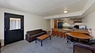 Located at 646 East College Avenue in State College, PA, this 910-square-foot apartment offers 2 bedrooms and 2 bathrooms across a single floor. The open-concept living area features carpet flooring, a dark leather sofa, coffee table, and flows seamlessly into the kitchen and dining space. The kitchen is equipped with wood-tone cabinetry, granite-style countertops, a black electric range, and a breakfast bar with barstool seating, complemented by hardwood-style flooring. A dining area with a round table sits adjacent to the kitchen.

The primary bedroom spans 230 square feet and includes a lofted bed frame with built-in drawer storage, a desk, and a window with vertical blinds allowing natural light. The second bedroom accommodates two occupants with two lofted bed frames, desks, and open wire shelving for storage. Both bedrooms are carpeted.

Two full bathrooms serve the unit — one featuring a tub/shower combo, vanity, and mirrored medicine cabinet, and the other equipped with grab bars for accessibility. A dedicated walk-in closet with wire shelving provides additional storage. The unit also includes a hallway connecting all rooms for a functional, efficient layout.