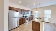 Located at 601-701 Water St in Seaford, Delaware, this 1-bedroom, 1-bathroom residence offers a thoughtfully designed single-floor layout that maximizes comfort and functionality. The open-concept floor plan seamlessly connects the kitchen and living room, creating an inviting and efficient use of space throughout.

The kitchen is a standout feature, showcasing rich dark-stained cabinetry, granite countertops, and a full suite of stainless steel appliances including a refrigerator, electric range, and built-in microwave. A peninsula with matching granite provides additional prep space and casual seating. Wood-look tile flooring and pendant lighting overhead add warmth and style to the area.

The living room is bright and welcoming, with plush carpeting, a ceiling fan, and large windows paired with a sliding glass door that floods the space with natural light and provides access to an outdoor balcony. Neutral wall tones throughout contribute to an airy, clean aesthetic.

The bedroom offers comfortable proportions, carpeted flooring, and a generously sized window with blinds for natural light and privacy. The bathroom is clean and functional, featuring a full tub-shower combination with a curved curtain rod. This residence presents a practical and modern living environment in a convenient Seaford location.
