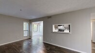Located at 500 Maxham Rd in Austell, Georgia, this one-bedroom, one-bathroom unit offers a well-organized single-floor layout designed for efficient living. Rich, dark hardwood-style flooring runs throughout the main living areas, complemented by neutral gray walls and clean white trim that create a modern, cohesive aesthetic.

The open living and dining areas are bathed in natural light from multiple windows fitted with horizontal blinds, offering views of surrounding greenery. A distinctive pass-through window connects the living area to the kitchen, enhancing the sense of openness. The kitchen features dark cabinetry, a tile backsplash with a geometric pattern, and black appliances including a range and refrigerator, all set beneath a textured ceiling.

The bedroom is a comfortable size, finished with plush carpeting, and includes a closet with additional natural light provided by a dual-pane window overlooking outdoor foliage. The bathroom is equipped with a full soaking tub and shower combination, accented by white subway tile surround and chrome fixtures.

A hallway connects the main rooms, and the unit includes a dedicated closet for additional storage. The overall layout is practical and well-proportioned, making it a functional and inviting living space.