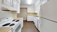 This single-floor residence offers a functional and comfortable layout designed for everyday living. The kitchen is well-equipped with white cabinetry, ample counter space, a full suite of appliances including an electric range, dishwasher, and refrigerator, all set atop durable hardwood-style flooring. An adjacent dining area with a chandelier provides an elegant transition between the kitchen and living spaces.

The living room features neutral-toned carpeting and a large sliding glass door dressed with vertical blinds, allowing abundant natural light to fill the room and providing direct access to the outdoors. A textured ceiling adds character throughout the common areas.

The bedrooms are carpeted and each include ceiling fans with light fixtures, offering both comfort and ventilation. Natural light enters through windows fitted with blinds. One bedroom benefits from direct access to a full bathroom as well as a dedicated walk-in closet, providing practical storage solutions.

The bathroom is clean and efficiently arranged, featuring a white vanity with storage cabinetry, a mirror, a toilet, and a tub-shower combination. Hardwood-style flooring continues into the bathroom, maintaining a cohesive aesthetic throughout the space. Overall, the residence presents a neutral, move-in-ready environment with consistent finishes across all rooms.