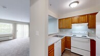 This single-floor unit offers a practical and well-organized layout across two bedrooms, one bathroom, and a combined kitchen and living area. The kitchen is efficiently designed with warm honey-toned oak cabinetry, light granite-style laminate countertops, a double-basin sink, a white electric range, dishwasher, and a full-size refrigerator. A pass-through counter separates the kitchen from the adjacent living area, enhancing the open feel between the two spaces. The living room features neutral-toned carpet, soft beige walls, and a sliding glass door with vertical blinds that allows generous natural light and outdoor views of surrounding greenery.

The primary bedroom is a comfortable size, equipped with a sliding glass door providing additional natural light and outdoor access, along with a wall-unit air conditioner. The second bedroom is more compact, featuring a window with garden views, plush carpet, and a closet. Both rooms maintain the same warm, neutral color palette found throughout the unit.

The bathroom features light wood-toned cabinetry, a tub-shower combination with tiled surround, and light vinyl plank flooring. A mirrored closet in the hallway provides additional storage. Throughout the unit, the consistent use of neutral tones, carpet, and natural light creates a cohesive and functional living environment.
