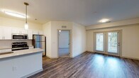 Located at 135 Donelson Pike in Nashville, TN, this single-floor unit offers a clean, functional layout with modern finishes throughout. The open-concept living and dining area is anchored by rich, wood-look plank flooring and flows seamlessly into a well-equipped kitchen. The kitchen features white shaker-style cabinetry, light countertops, a subway tile backsplash, stainless steel appliances including a refrigerator and microwave, and pendant lighting that adds a contemporary touch. A kitchen island provides additional workspace and visual separation from the living area, which is brightened by natural light from a glass-paneled exterior door. The bedrooms are finished with plush wall-to-wall carpeting and ceiling fans, offering a comfortable and quiet retreat. Windows dressed with blinds allow natural light while maintaining privacy. A spacious walk-in closet with wire shelving provides generous storage. The bathroom is neatly appointed with a subway-tiled soaking tub and shower combination, complemented by clean white fixtures. Neutral wall tones and consistent finishes throughout the space create a cohesive and move-in-ready environment suited for everyday living in Nashville.