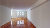 Located at 40 Barker Ave in White Plains, NY, this 2-bedroom, 1-bathroom residence offers a well-organized single-floor layout with classic design elements throughout. The spacious living area is a standout feature, showcasing richly polished hardwood floors that reflect natural light streaming in through large, multi-pane windows. Radiator heating units beneath the windows provide efficient warmth throughout the colder months. The layout flows naturally from the living area into a hallway connecting the bedrooms and additional spaces. Both bedrooms continue the warm hardwood flooring and are bright with natural light from windows overlooking the surrounding neighborhood. One bedroom includes a built-in closet, offering practical storage. The kitchen is equipped with white cabinetry extending to the ceiling for ample storage, a gas range, dishwasher, and a window that brings in additional natural light. Tile flooring completes the kitchen's clean, functional aesthetic. The bathroom features white subway tile walls, a tiled tub-shower combination, a vanity with under-sink storage, and a window for ventilation. The overall ambiance of the residence is clean and bright, with neutral white walls and gleaming wood floors creating a welcoming, move-in ready environment.
