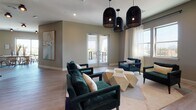 This elevated sky lounge is a thoughtfully designed communal space spread across a single floor, blending contemporary style with functional elegance. The open layout seamlessly connects a comfortable lounge area, a formal dining section, and a well-appointed kitchenette, creating a versatile environment suited for both relaxed gatherings and private events.

The living area features rich emerald green velvet seating arranged around sculptural geometric coffee tables, anchored by a patterned area rug and illuminated by dramatic woven pendant lights that hang from the ceiling. Large windows dressed with sheer white curtains flood the room with natural light while framing sweeping city skyline views. French doors open directly onto an outdoor terrace, extending the space and enhancing its airy ambiance.

The dining area is anchored by a long natural wood table surrounded by classic wooden chairs, positioned adjacent to full-height sliding glass doors that provide both abundant light and direct access to the terrace with open city vistas.

The kitchenette is distinguished by a striking textured wood-panel accent wall housing a mounted television, flanked by warm sconce lighting. Dark cabinetry with stone countertops and integrated appliances provide a refined, functional workspace. Light hardwood flooring flows consistently throughout, tying each zone together in a cohesive, modern aesthetic.