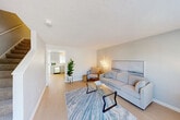 Located at 350 Main St in Spencer, MA, this multi-floor unit offers a practical and well-organized layout across three levels. The main living floor features a bright, open living room with light hardwood-style flooring, soft neutral tones, and a large window that allows natural light to fill the space. The kitchen is outfitted with crisp white shaker cabinetry extending to the ceiling, a stainless steel refrigerator, and light countertops, creating a clean and functional cooking area. The full bathroom includes a tub/shower combo, a vanity with storage, and light wood-style flooring for a tidy, understated finish. Upstairs, the two carpeted bedrooms offer comfortable retreats; the primary bedroom is generously sized with a window overlooking the grounds, while the second bedroom provides a cozy, quiet space. A hallway and closet add to the storage and circulation of the upper floor. The unfinished basement provides additional utility space with exposed structural elements and concrete flooring. Outside, the property features a spacious parking lot in front and a landscaped grassy yard at the rear, bordered by mature trees, offering a pleasant outdoor setting in a residential community.