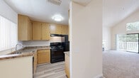 Located at 2851 Redwood Parkway in Vallejo, CA, this two-bedroom, two-bathroom two-story home offers a well-designed layout spread across two floors. The main level hosts the majority of the living space, including a combined dining and living area distinguished by soaring vaulted ceilings that create an open, airy atmosphere. A tile-surround fireplace anchors the living room, while a sliding glass door opens to an outdoor balcony, filling the space with natural light and outdoor views. The kitchen features light wood cabinetry, granite-style countertops, black appliances including a gas range and refrigerator, and durable wood-look flooring, with a pass-through that connects to the dining area. Both bathrooms are finished with wood-toned vanities, large mirrors, and light-toned flooring. The bedrooms offer plush carpeting and generous closet space, including walk-in and sliding-door closets. A staircase leads to the upper loft level, which houses the primary bedroom. Additional highlights include a dedicated laundry area, multiple hallways, five closets for ample storage, and a functional entrance. The textured ceilings and warm neutral palette throughout lend the home a cohesive, comfortable feel.