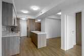 Located on the 9th floor at 49 Walnut Street South in Hamilton, Ontario, this thoughtfully designed unit offers a modern living experience with a clean, contemporary aesthetic throughout. Light wood-tone flooring runs continuously across the open-plan layout, complementing the neutral white walls and contributing to a bright, cohesive atmosphere.

The kitchen is a standout feature, showcasing a two-tone design with crisp white upper cabinetry paired with warm wood-grain lower cabinets. Quartz countertops, a subway tile backsplash, and a full suite of stainless steel appliances — including a built-in dishwasher, electric range, microwave, and refrigerator — complete the well-equipped space. A kitchen island with a wood-panel base provides additional prep and seating space, anchoring the open-concept living area.

The living area benefits from a large floor-to-ceiling window that frames expansive views of the Hamilton cityscape and surrounding greenery, flooding the room with natural light. The entry features a built-in wood-panel coat nook with hooks for added functionality.

The bathroom is finished in a clean, all-white palette with a full soaker tub and shower combination, chrome fixtures, and modern lever-style hardware. The overall layout is efficiently organized, making excellent use of the available space while maintaining a polished, contemporary feel throughout.