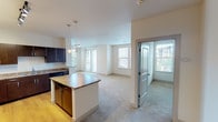 This single-floor residence is designed with an open-concept layout that seamlessly connects the kitchen, dining, and living areas. The kitchen is well-appointed with dark espresso cabinetry, granite-style countertops, hardwood flooring, and a full suite of appliances including a stainless steel refrigerator, black range, microwave, and dishwasher. A central island with pendant lighting above provides additional prep and dining space, while track lighting illuminates the full kitchen area.

The living room is generously sized with plush carpeting and features a sliding glass door opening to a private balcony, alongside multiple windows that invite abundant natural light and outdoor views. A dedicated entry area with a full-light door adds a welcoming transition into the home.

The bedrooms are carpeted and well-lit with large windows offering exterior views. One bedroom includes a ceiling fan, while another provides a quiet, neutral space suitable for varied uses. Both bathrooms are finished with tile flooring and dark wood vanities. The primary bathroom features a dual-sink vanity with a large mirror, a soaking tub, and a tiled shower-tub combination, while the secondary bathroom offers a tiled tub-shower unit with clean, simple finishes throughout.