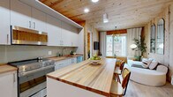 Located at 29 Crown Street in downtown New Haven, CT, this thoughtfully designed 2-bedroom, 2-bathroom residence makes a striking first impression with its signature architectural detail: expansive knotty pine wood ceilings and accent walls that carry warmth and texture throughout the entire single-floor layout. Light hardwood flooring complements the natural wood tones seamlessly.

The open-plan kitchen and living area serves as the heart of the home. The kitchen is outfitted with white flat-front cabinetry, stainless steel appliances including a gas range and dishwasher, rich butcher block countertops, and a large central island that doubles as a dining and prep space. The living area connects directly to this space, featuring floor-to-ceiling windows that frame city views and fill the room with natural light.

Both bedrooms offer generous windows with urban vistas and are finished with a mix of white walls and pine wood accents. The primary bedroom provides a comfortable retreat, while the second bedroom includes built-in desk space, ideal for a home office setup.

The two full bathrooms are clean and modern, each featuring a walk-in shower, white vanity, and light wood flooring. A dedicated laundry area and two closets add practical storage. A connecting hallway with recessed lighting and continued wood detailing ties the layout together cohesively.