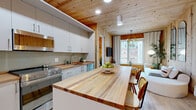 Located at 29 Crown Street in downtown New Haven, CT, this thoughtfully designed 2-bedroom, 2-bathroom residence makes a striking first impression with its signature architectural detail: expansive knotty pine wood ceilings and accent walls that carry warmth and texture throughout the entire single-floor layout. Light hardwood flooring complements the natural wood tones seamlessly.

The open-plan kitchen and living area serves as the heart of the home. The kitchen is outfitted with white flat-front cabinetry, stainless steel appliances including a gas range and dishwasher, rich butcher block countertops, and a large central island that doubles as a dining and prep space. The living area connects directly to this space, featuring floor-to-ceiling windows that frame city views and fill the room with natural light.

Both bedrooms offer generous windows with urban vistas and are finished with a mix of white walls and pine wood accents. The primary bedroom provides a comfortable retreat, while the second bedroom includes built-in desk space, ideal for a home office setup.

The two full bathrooms are clean and modern, each featuring a walk-in shower, white vanity, and light wood flooring. A dedicated laundry area and two closets add practical storage. A connecting hallway with recessed lighting and continued wood detailing ties the layout together cohesively.