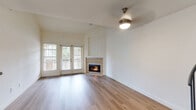 This two-story home in San Marcos, California offers a well-organized layout spread across two floors. The main level serves as the heart of the home, anchored by an open living room with light wood-style flooring, neutral walls, and a tile-surround fireplace framed by French doors that invite natural light and outdoor views. The adjacent kitchen is well-equipped with rich warm-toned wood cabinetry, granite countertops, a breakfast bar peninsula, and black appliances including a gas range, microwave, dishwasher, and refrigerator. A hallway connects the main living areas to two full bathrooms, one of which features warm wood cabinetry with granite countertops and a tub-shower combination. The upper level, accessed via a charming spiral staircase with a metal railing, houses the two bedrooms, both carpeted for comfort. The primary bedroom offers a generous footprint, while the secondary bedroom features vaulted ceilings and a window with natural light. The upper hallway is finished with the same light wood-style flooring seen downstairs, maintaining a cohesive design throughout. Clean white walls and consistent finishes give the entire home a bright, move-in-ready feel.