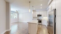 Located at 13385 Highlands Pl in San Diego, CA, this single-story space presents a cohesive modern design with a neutral palette and quality finishes throughout. The open-concept living and kitchen area serves as the heart of the home, where warm wood-look flooring flows seamlessly underfoot. The kitchen is outfitted with white shaker-style cabinetry reaching toward the ceiling, a herringbone tile backsplash, stainless steel appliances including a gas range, microwave, and French door refrigerator, and a central island with a light quartz countertop. Pendant lighting above the island and recessed ceiling lights enhance both function and ambiance, while a ceiling fan carries through to the adjoining living area, which receives natural light from a window overlooking greenery outside.

The bedrooms feature soft carpeting, ceiling fans, natural light from windows with blinds, and closets with built-in shelving. The bathroom is finished with large-format tile flooring laid in a herringbone pattern, a single vanity with quartz countertop and modern hardware, a large mirror, and a tub-shower combination. A dedicated laundry area with a stacked washer and dryer adds everyday convenience. Throughout, the space maintains a clean, contemporary aesthetic well-suited to the San Diego lifestyle.