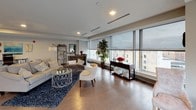 This single-floor urban residence showcases a contemporary design defined by expansive floor-to-ceiling windows that frame panoramic city views and flood the interior with natural light. Hardwood flooring flows throughout the main living areas, creating a warm and cohesive aesthetic.

The open-concept living and dining area is generously proportioned, with recessed lighting and wide window banks offering unobstructed views of the surrounding cityscape. The space transitions seamlessly into the kitchen, which features dark espresso cabinetry, a subway tile backsplash, stainless steel appliances, and a large granite-topped island with bar seating—ideal for both meal preparation and casual dining. Pendant lighting above the island adds a refined touch.

The bedrooms continue the floor-to-ceiling window theme, each offering city views and hardwood floors, creating bright and restful retreats. Two bathrooms serve the residence: one is a full bath with a walk-in glass shower, undermount sink, white quartz countertop, and dark cabinetry; the other is a spacious full bath with similar finishes, a grab bar, and generous floor space. Both feature large-format tile flooring. Overall, the residence presents a polished, modern ambiance throughout.