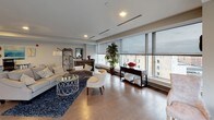 This single-floor urban residence showcases a contemporary design defined by expansive floor-to-ceiling windows that frame panoramic city views and flood the interior with natural light. Hardwood flooring flows throughout the main living areas, creating a warm and cohesive aesthetic.

The open-concept living and dining area is generously proportioned, with recessed lighting and wide window banks offering unobstructed views of the surrounding cityscape. The space transitions seamlessly into the kitchen, which features dark espresso cabinetry, a subway tile backsplash, stainless steel appliances, and a large granite-topped island with bar seating—ideal for both meal preparation and casual dining. Pendant lighting above the island adds a refined touch.

The bedrooms continue the floor-to-ceiling window theme, each offering city views and hardwood floors, creating bright and restful retreats. Two bathrooms serve the residence: one is a full bath with a walk-in glass shower, undermount sink, white quartz countertop, and dark cabinetry; the other is a spacious full bath with similar finishes, a grab bar, and generous floor space. Both feature large-format tile flooring. Overall, the residence presents a polished, modern ambiance throughout.
