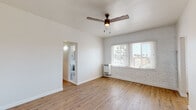 Located at 260 S Mariposa Ave in the Koreatown neighborhood of Los Angeles, this single-floor unit offers a clean, functional layout with a bright and open feel throughout. The main living area is generously proportioned, featuring warm light wood flooring, crisp white walls, and an accent wall of whitewashed brick that adds character and texture. A ceiling fan with integrated lighting anchors the room, while large windows fitted with slatted blinds allow abundant natural light and views of the surrounding neighborhood. A wall-mounted heater provides efficient climate control.

The kitchen is well-appointed with grey shaker-style cabinetry, white subway tile backsplash, and stainless steel appliances including a gas range and full-size refrigerator, all set on matching light wood flooring that flows seamlessly from the living area.

The bathroom is finished with floor-to-ceiling dark marble-style tile, lending a rich, polished aesthetic. It includes a soaking bathtub with a shower, a white vanity with an integrated sink, chrome fixtures, and a mirrored medicine cabinet. A window provides natural light and ventilation.

An additional room with its own ceiling fan and entry door offers flexibility as a bedroom or multipurpose space, completing this well-designed Los Angeles unit.