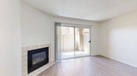 This single-story, one-bedroom, two-bathroom home in San Bernardino, California offers a well-organized layout with clean, neutral finishes throughout. The open living room serves as the heart of the home, featuring light wood-style flooring, a textured ceiling, and a tile-surround fireplace that adds a warm focal point to the space. A full-width sliding glass door bathes the room in natural light and provides direct access to a private outdoor patio, creating a seamless indoor-outdoor connection. The kitchen is efficiently designed with white cabinetry, speckled granite-style countertops, a stainless steel gas range with overhead ventilation, and a window that brings in additional natural light. The bedroom is carpeted for comfort, offering a quiet retreat with a large window fitted with vertical blinds. The primary bathroom is well-appointed with a wide vanity, dual under-mount sinks, a large mirror with overhead lighting, and white cabinetry with dark hardware. A separate tub-shower combo and toilet complete the bathroom. The second bathroom is compact and functional, also featuring a tub-shower combination. Throughout the home, the bright white walls and consistent flooring create a cohesive, move-in ready atmosphere.