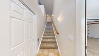 This two-story home offers a well-organized layout across two levels, with the majority of the living space situated on the upper floor. The ground level features a spacious attached garage with an automatic door opener and a clean concrete floor, along with a tiled entryway and carpeted staircase with a warm wood handrail leading to the main living areas above.

The upper floor hosts an open-concept kitchen and living room, where warm-toned wood cabinetry, light countertops, and tile flooring define the kitchen space. The layout flows naturally into the living area, making it well-suited for everyday living and entertaining.

Both bedrooms are generously proportioned and finished with plush carpeting and neutral walls. Each room benefits from natural light through large windows, with the primary bedroom offering notable space and a dedicated walk-in closet equipped with wire shelving for organized storage. Additional closets throughout provide ample storage capacity.

The three bathrooms are finished with warm tile flooring and white cabinetry. One bathroom features a tub-shower combo, while another includes a sliding glass-door shower enclosure, offering variety in fixtures and function. Ceiling fans in the bedrooms add comfort, and the consistent use of neutral tones throughout creates a clean, cohesive aesthetic across the entire home.