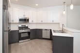 Located at 18831 Von Karman Ave in Irvine, CA, this thoughtfully designed one-bedroom, one-bathroom residence offers a clean, modern aesthetic throughout. The open-concept kitchen and living area serves as the heart of the home, featuring two-tone cabinetry with crisp white upper cabinets and charcoal lower cabinets, bright white quartz countertops, and stainless steel appliances including a gas range, microwave, and dishwasher. Stylish pendant lights and recessed lighting illuminate the space, while light wood-style flooring adds warmth underfoot. A sliding glass door in the living area opens to a private balcony overlooking a well-landscaped courtyard surrounded by the building's contemporary multi-story architecture. The bedroom is a comfortable retreat with plush carpet flooring, a ceiling fan, and windows that invite natural light. It connects directly to a spacious walk-in closet outfitted with multi-level shelving and hanging rods for generous storage. The bathroom is clean and functional, featuring a full soaking tub with shower, light wood-style flooring, and a vanity. A hallway connects all areas of the residence, completing this efficiently laid-out and move-in-ready Irvine home.