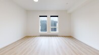 This contemporary apartment offers 740 square feet of efficiently designed living space. The open-concept layout combines the kitchen and living area, creating a spacious feel. The kitchen boasts a sleek design with white upper cabinets contrasting light wood lower cabinets, stainless steel appliances, and a subway tile backsplash. Three bedrooms provide ample space, with the primary bedroom measuring 130 square feet. The single bathroom features a modern vanity and a glass-enclosed shower/tub combination. Throughout the apartment, light wood-look flooring adds warmth and continuity. Large windows in the bedrooms and living area allow natural light to flood the space, while offering views of the surrounding area. The apartment is equipped with a wall-mounted air conditioning unit for comfort. Sliding closet doors in the bedrooms maximize space efficiency. The neutral color palette and clean lines contribute to the overall modern aesthetic of this well-appointed Vernon, BC residence.