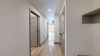 Located at 777 E 17th Ave in Denver's vibrant Capitol Hill neighborhood, this two-story residence offers a thoughtfully designed layout across a generously sized main floor and an upper-level loft-style bedroom. The main floor makes an immediate impression with dramatic double-height ceilings, light-toned hardwood flooring, and floor-to-ceiling windows paired with transom windows above that flood the space with natural light. A private balcony access via full-height glass doors extends the living area outdoors. An exposed concrete column adds an industrial-modern character to the open living area. The kitchen features crisp white cabinetry with black hardware, a subway tile backsplash, stainless steel appliances including a refrigerator, range, microwave, and dishwasher, and a modern pendant light overhead. An interior railing overlooks the main floor from the upper level, maintaining visual connectivity. The bedroom is carpeted and includes a ceiling fan, a closet, and access to the hallway. The bathroom is finished with light wood-look flooring, gray cabinetry, a white quartz countertop, a large framed mirror, and a full tub-shower combination with matte black fixtures throughout. Clean, neutral tones and modern finishes define the overall aesthetic of this well-appointed Denver residence.