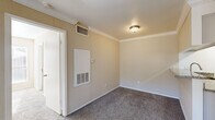 Located at 7100 Almeda Rd in Houston, TX, this one-bedroom, one-bathroom unit offers a well-organized layout that makes efficient use of its space. The living room serves as the heart of the home, featuring warm neutral-toned walls, crown molding, plush carpet flooring, and a classic fireplace with a white mantel. A sliding glass door floods the room with natural light and opens to an outdoor patio area. The galley-style kitchen is well-appointed with white cabinetry, granite countertops, black appliances including a refrigerator, electric range, and built-in microwave, complemented by light wood-look tile flooring and a narrow window that brings in additional natural light. The bedroom is carpeted and bright, with a ceiling fan, a large window with outdoor views, and access to a dedicated closet. The bathroom features a granite-topped vanity with white cabinetry, an undermount sink, and a large mirror, maintaining a consistent, clean aesthetic throughout. Crown molding and neutral warm tones unify the space, creating a cohesive and comfortable living environment suited for everyday living.