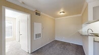 Located at 7100 Almeda Rd in Houston, TX, this one-bedroom, one-bathroom unit offers a well-organized layout that makes efficient use of its space. The living room serves as the heart of the home, featuring warm neutral-toned walls, crown molding, plush carpet flooring, and a classic fireplace with a white mantel. A sliding glass door floods the room with natural light and opens to an outdoor patio area. The galley-style kitchen is well-appointed with white cabinetry, granite countertops, black appliances including a refrigerator, electric range, and built-in microwave, complemented by light wood-look tile flooring and a narrow window that brings in additional natural light. The bedroom is carpeted and bright, with a ceiling fan, a large window with outdoor views, and access to a dedicated closet. The bathroom features a granite-topped vanity with white cabinetry, an undermount sink, and a large mirror, maintaining a consistent, clean aesthetic throughout. Crown molding and neutral warm tones unify the space, creating a cohesive and comfortable living environment suited for everyday living.