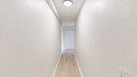 Located at 100 Old York Road in Jenkintown, PA, this two-bedroom, one-bathroom unit offers a well-organized single-floor layout with a clean, neutral aesthetic throughout. Light-toned hardwood flooring flows consistently across the living areas, bedrooms, and hallway, creating a cohesive and airy feel.

The combined kitchen and living room area serves as the heart of the unit. The kitchen is equipped with stainless steel appliances — including a gas range, over-the-range microwave, and refrigerator — complemented by warm honey-toned wood cabinetry and granite-style countertops atop tile flooring. The living room is generously proportioned, featuring recessed lighting, a baseboard heating system, and large windows dressed with vertical blinds that allow ample natural light and offer views of the surrounding greenery.

Both bedrooms continue the hardwood flooring theme and maintain the unit's bright, neutral palette. The primary bedroom is notably spacious, featuring dual windows on adjacent walls that maximize light and outdoor views. A sliding double-door closet provides practical storage. The second bedroom is well-sized with a standard closet.

The bathroom includes a full tub and shower combination with clean white tile surround and a wood-framed vanity. A connecting hallway with flush-mount ceiling lighting ties all rooms together efficiently.