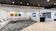 Located at 13682 Fraser Hwy in Surrey, BC, this thoughtfully designed amenity space spans a generous single floor, offering a dynamic blend of social, recreational, and lounge areas. The interior showcases a contemporary aesthetic characterized by crisp white walls, dark exposed ceilings with industrial-style ductwork and black piping, and a sophisticated combination of light hardwood flooring and patterned carpet tiles throughout.

The welcoming lounge area features plush modular grey sofas accented with colorful cushions, complemented by curated artwork and large-format display screens mounted on the walls. A reception-style counter anchors the space, adding a polished, professional touch. Adjacent seating nooks with additional sofas and accent tables provide inviting spaces for casual gatherings.

The recreational area is a standout highlight, equipped with a billiards table, a ping pong table, and a foosball table, all set within an open, light-filled zone with floor-to-ceiling windows offering outdoor views. A glass-walled room provides a dedicated, semi-private area for table tennis. The space also includes a private room, storage closet, and additional flex areas. Throughout, recessed and track lighting ensures a bright, welcoming atmosphere suited to both relaxation and active recreation.
