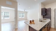 Located at 4947 Stewart Mill Rd in Douglasville, Georgia, this single-floor, 2-bedroom, 2-bathroom home offers a clean, modern aesthetic throughout. Light-toned hardwood-style flooring flows seamlessly across every room, complementing the neutral, warm white walls that create a bright and airy atmosphere.

The open kitchen is outfitted with rich dark espresso cabinetry, granite-style countertops, stainless steel appliances including a full-size refrigerator and gas range, and an over-the-range microwave — providing a fully functional cooking space. The adjacent living room is generously proportioned, featuring a ceiling fan and a large window that invites abundant natural light.

Both bedrooms are comfortably sized, with the primary bedroom offering ample room for furnishings. Each room is fitted with ceiling fans and windows dressed with horizontal blinds. The two bathrooms mirror each other in design, each showcasing dark espresso vanity cabinetry, granite-topped sinks, large mirrors, and a tub/shower combination. The hardwood-style flooring extends into both bathrooms for a cohesive look.

A dedicated laundry room houses a full-size top-load washer and overhead wire shelving for added storage. Two closets provide additional organization throughout the home. The overall layout is efficient and well-structured, making excellent use of every square foot.