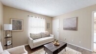 This one-bedroom, one-bathroom unit in Austin, TX offers a thoughtfully organized single-floor layout designed to maximize every square foot. The living room welcomes you with warm-toned beige walls, wood-look flooring, and a textured ceiling that adds character to the space. A front-facing window dressed with white grommet curtains allows natural light to fill the room, creating a bright and inviting atmosphere.

The open layout connects the living area to a dedicated dining space, making the unit feel cohesive and functional. The kitchen features white cabinetry, speckled countertops, and black appliances including an electric range and refrigerator, offering a practical cooking space.

The bedroom is carpeted for comfort and is highlighted by a full-width sliding glass door with vertical blinds that opens to a private patio, providing outdoor views and an abundance of natural light. A walk-in closet with built-in shelving and hanging rods offers generous storage directly adjacent to the bathroom, which includes a vanity with matching speckled countertops and a mirrored medicine cabinet.

Throughout the unit, the neutral color palette and consistent finishes create a calm, cohesive ambiance well-suited for comfortable everyday living in Austin.