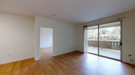 Located at 5210 San Viciente Loop in Dublin, CA, this single-floor residence offers a clean, contemporary design throughout. Warm wood-style flooring runs continuously across the living areas, bedrooms, and hallways, lending a cohesive and inviting feel to the entire space.

The open living area is bright and airy, benefiting from a large sliding glass door that opens onto a private balcony, framing views of lush greenery and the surrounding neighborhood. Natural light flows generously into the connected rooms, enhancing the space's welcoming ambiance.

The kitchen is well-appointed with white cabinetry, dark countertops, a tile backsplash, and a full suite of stainless steel appliances including a gas range, microwave, refrigerator, and dishwasher. A pass-through counter connects the kitchen to the adjacent living area, supporting an open and functional layout.

The bedrooms are generously sized, each featuring large windows that invite natural light and offer pleasant outdoor views of trees and landscaping. Hallway areas provide closet space for added storage convenience.

Two bathrooms serve the residence — one featuring a soaking tub with a sleek sliding glass enclosure and modern chrome fixtures, and a second full bathroom with a tub-shower combination, vanity with storage, and wood-style flooring that mirrors the rest of the home.