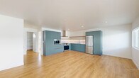 Located in the heart of Hollywood at 1422 Tamarind Ave, this thoughtfully designed one-bedroom, one-bathroom unit offers a clean, modern aesthetic throughout. Light oak hardwood flooring flows seamlessly across the entire space, enhancing its bright and airy feel. The open-concept kitchen and living area forms the heart of the unit, where a well-appointed kitchen stands out with bold teal flat-front cabinetry, a white subway tile backsplash, a natural wood open shelf, stainless steel appliances including a gas range with hood and a full-size refrigerator, and ample storage via floor-to-ceiling cabinetry. The generous living area benefits from abundant natural light, with a sliding glass door that opens directly onto a private balcony. The bedroom is a comfortable, sun-filled retreat featuring a wide mirrored sliding-door closet and a wall-mounted AC unit. The bathroom is finished with floor-to-ceiling vertical white tile surrounding a soaking tub and shower, built-in shelving, and clean modern fixtures. A dedicated in-unit laundry area adds everyday convenience. The overall ambiance is contemporary and minimalist, with a bright, neutral palette that makes the space feel open and welcoming.