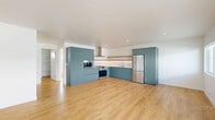 Located in the heart of Hollywood at 1422 Tamarind Ave, this thoughtfully designed one-bedroom, one-bathroom unit offers a clean, modern aesthetic throughout. Light oak hardwood flooring flows seamlessly across the entire space, enhancing its bright and airy feel. The open-concept kitchen and living area forms the heart of the unit, where a well-appointed kitchen stands out with bold teal flat-front cabinetry, a white subway tile backsplash, a natural wood open shelf, stainless steel appliances including a gas range with hood and a full-size refrigerator, and ample storage via floor-to-ceiling cabinetry. The generous living area benefits from abundant natural light, with a sliding glass door that opens directly onto a private balcony. The bedroom is a comfortable, sun-filled retreat featuring a wide mirrored sliding-door closet and a wall-mounted AC unit. The bathroom is finished with floor-to-ceiling vertical white tile surrounding a soaking tub and shower, built-in shelving, and clean modern fixtures. A dedicated in-unit laundry area adds everyday convenience. The overall ambiance is contemporary and minimalist, with a bright, neutral palette that makes the space feel open and welcoming.