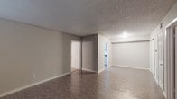 This single-floor unit offers a practical and functional layout across several distinct spaces. The main living area is generously sized, featuring durable vinyl flooring in a stone-like finish, neutral gray walls, and a textured popcorn ceiling. Natural light enters through a large window near the front entry door, and open doorways connect the living space to adjacent rooms, creating an easy flow throughout.

The kitchen is equipped with gray cabinetry, dark granite-style countertops, a stainless steel sink, and ample upper and lower cabinet storage. The bedrooms are carpeted and feature ceiling fans with integrated lighting. Each bedroom includes a window fitted with blinds, providing natural light and privacy. The rooms offer comfortable proportions suitable for standard furnishings.

Two full bathrooms serve the unit. One features tile-surround tub and shower combination with warm beige tiling, vinyl flooring, and standard fixtures. The second bathroom mirrors this layout with a tub/shower combo, a vanity with granite-style countertops, and vinyl flooring. Throughout the unit, white trim and baseboards provide clean contrast against the neutral gray walls, contributing to a cohesive and understated aesthetic.