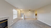This thoughtfully designed home features three bedrooms, two bathrooms, and a practical single-floor layout that maximizes everyday functionality. Neutral-toned walls, plush carpeting, and consistent finishes throughout create a cohesive and comfortable ambiance.

The living room is a generously sized space highlighted by a tiled fireplace and sliding glass doors that invite natural light and provide access to an outdoor area. A ceiling fan adds comfort to the room, which connects conveniently to the kitchen.

The galley-style kitchen is well-equipped, featuring white shaker cabinetry, dark granite countertops, light hardwood-style flooring, and a full suite of stainless steel appliances. A doorway from the kitchen leads directly into the dedicated laundry room, which includes a full-size washer and dryer and additional shelving.

The primary bedroom offers a comfortable footprint with a walk-in closet fitted with dual clothing rods and shelving. Secondary bedrooms are carpeted and include built-in closets with bi-fold doors. Both bathrooms feature granite countertops and white cabinetry consistent with the home's overall design. A carpeted staircase with a white handrail completes the layout.
