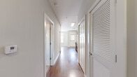 This one-bedroom, one-bathroom unit is thoughtfully laid out across a single floor, maximizing functionality within a compact footprint. The interior is finished with warm hardwood flooring throughout the main living areas, complementing the neutral wall tones that create a bright, cohesive aesthetic.

The kitchen is well-appointed, featuring rich dark-wood cabinetry, granite countertops, a white subway tile backsplash, and a full suite of stainless steel appliances including a refrigerator, electric range, built-in microwave, and dishwasher. The kitchen opens directly into the living area, supporting an efficient, open-concept flow.

A central hallway connects the main living space to the bedroom and bathroom, with a louvered-door closet providing dedicated storage. The hallway is finished with recessed lighting and hardwood flooring, maintaining the unit's consistent design language.

The bedroom features neutral carpet, a window with blinds for natural light and privacy, and a ceiling fan with integrated lighting. The bathroom is finished with hexagonal marble-look tile flooring and includes a full soaking tub with shower, framed by clean white surrounds and warm-toned walls.