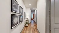 Located at 3233 Harmon Ave in Austin, TX, this one-bedroom, one-bathroom residence offers a smartly organized single-floor layout with consistent wood-look flooring and a clean, modern aesthetic throughout. The welcoming hallway sets an stylish tone, featuring recessed lighting, crisp white walls, and gallery-style framed artwork — a detail that carries an artistic sensibility into the home from the moment you enter. The living room is a bright, comfortable gathering space anchored by large windows that invite abundant natural light and offer views of the surrounding neighborhood. The bedroom provides a cozy retreat with warm tones, wood-look flooring, and ample wall space suited for personal décor. A dedicated closet offers built-in shelving and hanging rods, providing well-organized storage. The bathroom features a white quartz-topped vanity with contemporary cabinetry, tiled flooring, and a full shower, all finished in a cohesive, neutral palette. A dedicated laundry area houses a full-size GE front-loading washer and dryer with overhead shelving for added convenience. The kitchen, visible in the layout overview, integrates seamlessly into the open flow of the living areas, completing this efficient and attractive Austin residence.