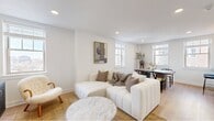 Located in Philadelphia's desirable Rittenhouse Square neighborhood, this well-appointed one-bedroom, one-bathroom residence offers a thoughtfully designed single-floor layout. Light wood flooring and a crisp white palette flow consistently throughout, creating a bright, cohesive aesthetic.

The open-concept living and dining area is the heart of the home, bathed in natural light from multiple windows framing city skyline views. The living space accommodates comfortable seating alongside a defined dining area, making it ideal for both relaxing and entertaining.

The kitchen is outfitted with full-height white cabinetry, dark countertops, a classic white subway tile backsplash, and a complete suite of stainless steel appliances including a range, built-in microwave, dishwasher, and side-by-side refrigerator, all complemented by a professional-style ventilation hood.

The bedroom features a large built-in sliding-door closet and connects seamlessly to the rest of the unit via the hallway. The bathroom offers a standout glass-enclosed walk-in shower finished in floor-to-ceiling marble-look tile with built-in shelving.

The entry hallway includes a louvered interior door and a built-in bench, providing a refined transition into the main living space.
