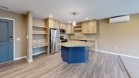 Located at 1130 County Road 4 in St. Cloud, Minnesota, this one-bedroom, one-bathroom unit offers a well-designed layout that maximizes comfort and functionality. The open-concept kitchen and living room serve as the heart of the space, where light wood cabinetry, granite countertops, and stainless steel appliances complement a bold navy blue island with pendant lighting overhead. Luxury vinyl plank flooring flows throughout the kitchen and dining area, transitioning to plush carpet in the living room. A wall-mounted mini-split unit provides additional climate control. The living room is highlighted by a sleek built-in electric fireplace with a light wood surround and recessed lighting above. A sliding glass door opens to a private balcony, offering open views of the surrounding St. Cloud landscape. The bedroom features soft carpet, a natural light-filled window, and access to a walk-in closet framed by an elegant arched entryway. The full bathroom includes granite countertops, a vanity with wood cabinetry, a tub/shower combo, tile flooring, and a convenient stacked washer and dryer tucked within the same space. Warm neutral tones and clean finishes create a cohesive and inviting atmosphere throughout.