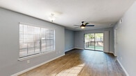 Located at 9988 Windmill Lakes Blvd in Houston, TX, this single-story, 2-bedroom, 4-bathroom home offers a well-designed layout with a comfortable and functional living experience. The open living and dining area is highlighted by warm wood-look flooring, a ceiling fan with light fixture, and abundant natural light streaming through wide windows with blinds and a sliding glass door that opens directly to the outdoors. The kitchen features white cabinetry, light quartz-style countertops, a gray subway tile backsplash, and stainless steel appliances including a range, over-the-range microwave, and refrigerator. Both bedrooms are carpeted and equipped with ceiling fans, large windows, and sliding panel closets that provide generous storage. The bathrooms include clean white fixtures, a tub-shower combination, and updated vanities with framed mirrors. A dedicated laundry area and four closets add to the home's practicality. The textured ceilings complement the neutral gray wall palette throughout. Outside, a private fenced backyard with a slatted wood fence opens to a lush green lawn surrounded by mature trees, offering a serene and shaded retreat.