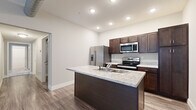 Located at 760 Main St in Charlestown, Indiana, this single-floor residence offers a thoughtfully designed layout with 2 bedrooms, 2 bathrooms, a kitchen, utility room, hallway, and closet. The kitchen serves as the heart of the home, showcasing rich dark-espresso cabinetry, light granite countertops, a central island with a built-in sink, and a full suite of stainless steel appliances including a French door refrigerator, electric range, and over-the-range microwave. Wood-look plank flooring runs throughout the main living and kitchen areas, adding warmth and durability. The primary bedroom offers a comfortable, carpeted retreat with natural light from large windows fitted with blinds. The second bedroom also features plush carpet, neutral tones, and a built-in closet with shelving. Both bathrooms are finished in clean, contemporary style — one includes a walk-in shower with a white surround, a dark vanity, and wood-look flooring, while the second features a full soaking tub and shower combination. Recessed lighting throughout enhances the bright, airy atmosphere. The utility room provides added functionality, completing this efficiently designed and move-in-ready home.