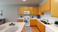 Located at 700 Emerald St SE in Saint Paul, Minnesota, this single-floor residence offers a thoughtfully designed layout with a welcoming, functional flow throughout. The living area is bathed in natural light from large windows that frame views of the surrounding neighborhood, creating an open and airy atmosphere. Warm hardwood-style flooring runs through the main living spaces, complementing the neutral wall tones and adding a sense of cohesion to the interior.

The kitchen is well-equipped and efficiently designed, featuring warm maple cabinetry, white appliances including a range, microwave, refrigerator, and sink, all set against clean white countertops. A central island with seating for two provides a convenient casual dining option and adds extra workspace. Recessed lighting overhead keeps the kitchen bright and functional.

The bedroom is a comfortable, carpeted retreat with a large window that invites natural light and outdoor views. Adequate closet space and a wall-mounted mirror contribute to the room's practicality.

The bathroom is finished with a dual-sink vanity topped with white counters, warm maple cabinetry, a large mirror, and a walk-in shower, all accented by warm tile flooring. The overall design of this residence prioritizes comfort, practicality, and a clean, modern aesthetic suitable for everyday living.