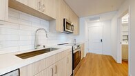 This contemporary studio in Folsom, California presents a thoughtfully designed single-floor layout that maximizes every square foot through clean lines and a bright, open aesthetic. Light wood-tone flooring runs throughout the entire unit, unifying the space and enhancing its airy feel.

The combined kitchen and living area forms the heart of the studio. The kitchen is outfitted with a full suite of stainless steel appliances, including a refrigerator, dishwasher, electric range with oven, and an over-the-range microwave. Light wood cabinetry extends from floor to ceiling, providing generous storage, while a white subway tile backsplash adds a modern, clean-cut accent. A stainless steel sink with a pull-down faucet and light-toned countertops complete the well-appointed cooking space.

The open living area is bathed in natural light courtesy of large windows that offer views of the surrounding neighborhood. The white walls and recessed lighting contribute to the bright, neutral ambiance throughout.

The bathroom features a full bathtub and shower combination with white tile surround and chrome fixtures, complemented by built-in open shelving for convenient storage.

Overall, this studio delivers a modern, minimalist design with functional finishes in a well-located Folsom address.