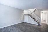 This two-story, 4-bedroom, 2-bathroom home in Atlanta, GA is thoughtfully laid out across two floors, offering a functional and comfortable living arrangement. The main floor features an open living area with light gray luxury vinyl plank flooring, neutral-toned walls, and a staircase with white baluster railings leading to the upper level. The kitchen is well-appointed with white shaker-style cabinetry, granite-look countertops, a stainless steel sink, and black appliances including an electric range and refrigerator, all set over matching LVP flooring. Natural light filters in through horizontal and vertical blinds throughout the home. The upper floor hosts the bedrooms, each featuring plush carpeting, ceiling fans with lighting, and windows that bring in natural light. The spacious primary bedroom includes a full closet with hanging rod storage. Additional bedrooms offer similar carpeted comfort and ceiling fan fixtures. A bedroom on the lower level features LVP flooring and a closet with louvered doors. Both bathrooms are clean and bright, with one featuring a full tub-shower combo, white tile surround, and wood-look tile flooring. A hallway connects the upper-level rooms efficiently, completing this well-organized home.