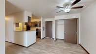 This single-floor residential unit offers a thoughtfully designed open-concept layout that seamlessly connects the living area to the kitchen. The living space features light wood-look luxury vinyl plank flooring that transitions to plush carpeting, with a ceiling fan providing both comfort and ambiance. A wall-mounted HVAC unit ensures year-round climate control.

The galley-style kitchen is well-equipped with dark espresso cabinetry, granite-look countertops, and a full suite of stainless steel appliances including a refrigerator, electric range, microwave, and dishwasher. A peninsula counter provides additional prep space and a natural divide between the kitchen and living area. Entryway closet storage is conveniently located just inside the front door.

The bedrooms are generously sized, each featuring plush carpeting, ceiling fans, natural light from windows with blinds, and baseboard heating. One bedroom includes a large walk-in closet with dual hanging rods, offering ample storage capacity.

The bathroom is clean and functional, featuring wood-look tile flooring, a full soaking tub with shower surround, granite-look vanity countertop, dark cabinetry, and additional overhead storage. The overall aesthetic is clean and modern, with a neutral color palette creating a bright and welcoming atmosphere throughout.