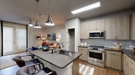 This single-story residence in Yulee, Florida offers a thoughtfully designed open-concept layout that seamlessly connects the kitchen, dining, and living areas. The kitchen serves as a central hub, featuring a large island with a deep undermount sink, dark quartz countertops, and seating for multiple bar stools beneath industrial-style brushed nickel pendant lights. Light wood-tone cabinetry pairs with a gray subway tile backsplash, while stainless steel appliances—including a French door refrigerator, range, and built-in microwave—complete the space. A walk-in pantry with built-in shelving provides ample storage.

The living area extends naturally from the kitchen, finished with wood-look plank flooring and anchored by French doors that allow natural light to fill the space. A ceiling fan overhead adds functional comfort.

The bedroom is carpeted for warmth and features large windows with blinds and draping curtains, a ceiling fan, and access to a generously sized walk-in closet with wire shelving systems. The bathroom showcases a wide wood-tone vanity with dark countertops, an undermount sink, a large mirror, and a glass-enclosed walk-in shower with white subway tile walls. Consistent neutral tones and modern finishes create a cohesive, contemporary ambiance throughout.