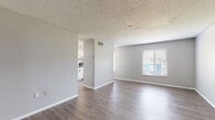 Located at 828 Orienta Ave in Altamonte Springs, Florida, this single-floor unit offers a practical and well-maintained layout with modern updates throughout. The open living area is defined by durable wood-look laminate flooring, neutral gray walls, and clean white baseboards that lend a fresh, cohesive aesthetic. A textured popcorn ceiling adds a classic touch, while a sizable window fitted with horizontal blinds allows natural light to fill the space. The living area flows naturally toward the kitchen, which is visually separated by a partial dividing wall. The kitchen is equipped with white shaker-style cabinetry, a subway tile backsplash, dark countertops, and stainless steel appliances including a range and refrigerator. An additional window in the kitchen provides further natural light and outdoor views. A separate room with its own door offers flexibility as a bedroom or private space, featuring the same wood-look flooring and neutral wall tones. The bathroom includes a white vanity with an integrated sink, a wood-framed mirror, and a shower-tub combination with a curtain enclosure. Throughout the unit, the consistent use of light gray tones, updated flooring, and functional fixtures creates a clean, move-in ready environment suited for comfortable everyday living.